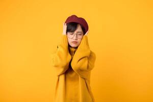 ung 30s asiatisk kvinna studerande uttryck desperat emotionell påfrestning känsla med stängd öra med hand för tystnad till höra en ljud ljud mot gul bakgrund. olycklig desperat gest begrepp. foto