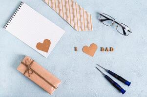 fars dag gåva, anteckningsbok, slips, glasögon, skruvmejslar och inskrift på blå bakgrund foto
