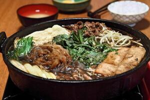 sukiyaki, japansk maträtt med skivad filet, Smör, soja sås, socker, shitake, mangold och tofu foto