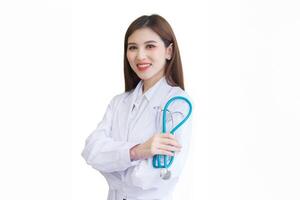 ung asiatisk professionell kvinna läkare stående självsäkert med vapen korsade bär vit morgonrock och stetoskop på undersökning rum i sjukhus medan isolerat vit bakgrund. foto