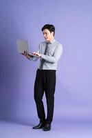 porträtt av asiatisk manlig affärsman stående och Framställ på lila bakgrund foto