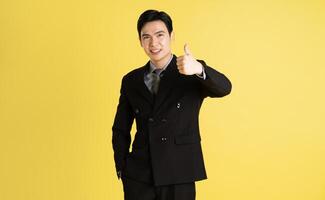 porträtt av asiatisk manlig affärsman. bär en kostym och Framställ på en gul bakgrund foto