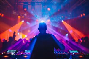 manlig dj på en stor rave spelar för en stor folkmassan av fest människor, ravers dans, stor laser visa foto