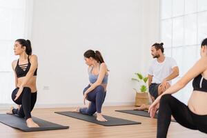 en yoga lärare och henne grupp av studenter do grundläggande yoga poser i en klassrum i en kondition Centrum i de studio. foto