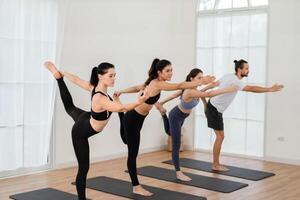 en yoga lärare och henne grupp av studenter do grundläggande yoga poser i en klassrum i en kondition Centrum i de studio. foto