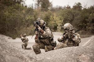 soldater i kamouflage uniformer siktar med deras gevär redo till brand under militär drift i de öken- soldater Träning i en militär drift foto