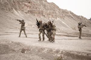 soldater i kamouflage uniformer siktar med deras gevär redo till brand under militär drift i de öken- soldater Träning i en militär drift foto