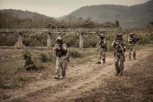 soldater i kamouflage uniformer siktar med deras gevär redo till brand under militär drift i de skog soldater Träning i en militär drift foto