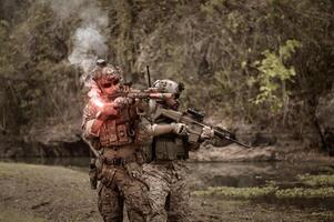 soldater i kamouflage uniformer siktar med deras gevär redo till brand under militär drift i de skog soldater Träning i en militär drift foto