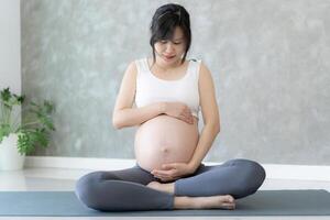 gravid kvinna håller på med yoga på övning matta. mediterar för på kort sikt förlossning av mediterar attraktiv gravid kvinna rekreation och koppla av, andas och lugna med yoga. själv vård foto