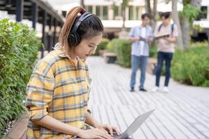 skön asiatisk kvinna kvinna studerande upphetsad kontroll språk testa resultat på bärbar dator. leende flicka Lycklig studie uppkopplad. bok i högskola campus. porträtt kvinna på internationell Asien universitet. foto