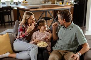 mysigt familj tid, delning skratt och popcorn på en tillfällig kväll foto