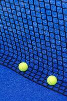 två bollar Nästa till en paddla tennis domstol netto, racket sporter begrepp foto