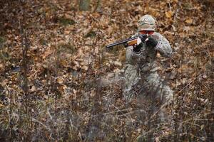 jakt, krig, armén och människor begrepp - ung soldat, ranger eller jägare med pistol gående i skog foto