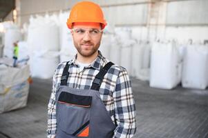 leende och Lycklig anställd. industriell arbetstagare inomhus i fabrik. ung tekniker med hård hatt foto