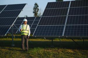 industriell senior man ingenjör gående genom sol- panel fält för undersökning foto