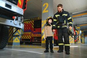 brandman innehav barn pojke till spara honom i brand och rök, brandmän rädda de Pojkar från brand foto