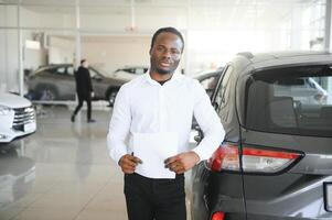 ung afrikansk amerikan bil återförsäljare rektor stående i fordon utställningslokal foto