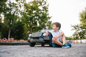 söt pojke i ridning en svart elektrisk bil i de parkera. rolig pojke rider på en leksak elektrisk bil. kopia Plats. foto