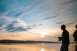 fiske. spinning på solnedgång. silhuett av en fiskare. foto