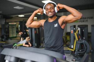 atletisk man stående i en Gym lyssnande till musik använder sig av trådlös hörlurar foto