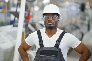 afrikansk manlig ingenjör. kontrollera en material produktion maskin systemet, arbetssätt i en plast och stål industri angående de företagets produkt företag. foto