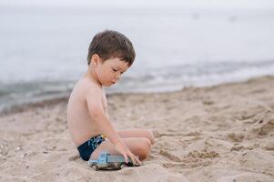 söt bebis pojke spelar leksaker på strand. foto