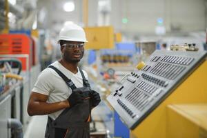 porträtt av industriell ingenjör. leende fabrik arbetstagare med hård hatt stående i fabrik produktion linje foto