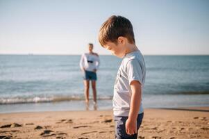 mor och son spelar på de strand på de solnedgång tid. begrepp av vänlig familj foto