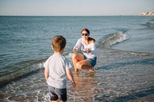 mor och son spelar på de strand på de solnedgång tid. begrepp av vänlig familj. foto