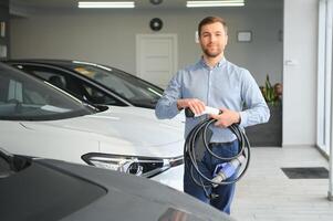 ung man, försäljning elektrisk bilar i de showroom. begrepp av uppköp miljövänlig bil för familj foto