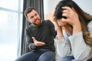 emotionell man gestikulerar och skrikande på hans fru, ung par har gräl på Hem. inhemsk missbruk begrepp foto