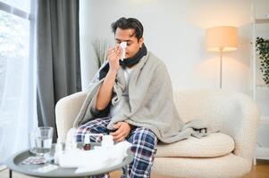 hälsa, kall och människor begrepp - sjuk ung indisk man i filt har huvudvärk eller feber på Hem foto