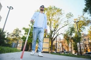 blind man gående på trottoar innehav pinne. foto