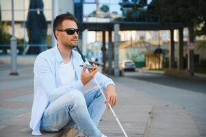 ung blind man med smartphone i stad, kallelse foto