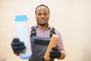afrikansk amerikan rörmokare innehav ny och Begagnade vatten filter foto