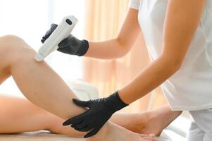 en kosmetolog gäller vax till en skön kvinnas ben. de begrepp av depilation foto