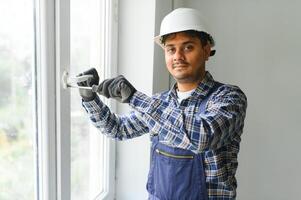 indisk service man montera fönster med skruvmejsel foto