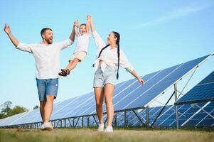 Lycklig familj nära sol- paneler. alternativ energi källa foto