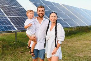 ung familj av tre är hukande nära solceller sol- panel, liten pojke och föräldrar. modern familj begrepp. de begrepp av grön energi foto