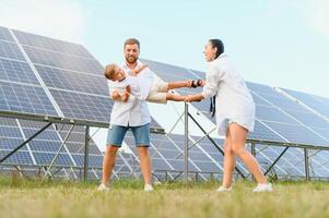 Lycklig familj nära sol- paneler. alternativ energi källa foto