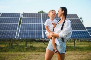 Lycklig mor och henne liten son är gående nära de sol- paneler. de begrepp av grön energi. foto