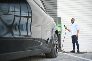 man plugging i elektrisk bil utanför kontor i bil parkera laddning foto