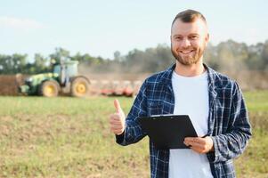 lantbruk. jordbrukare arbetssätt i en fält i de bakgrund traktor plogar jord i en fält av vete. jordbruk lantbruk begrepp. företag jordbrukare i de fält foto