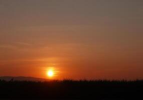 spektakulär solnedgång över, orange Sol stigande upp över de horisont foto