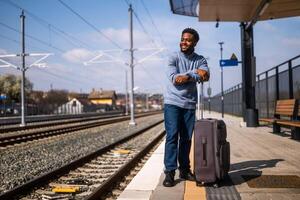 Lycklig man med resväska stående på järnväg station. foto