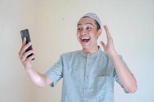 moslem asiatisk man Lycklig under ring upp med smartphone när ramadan firande. foto