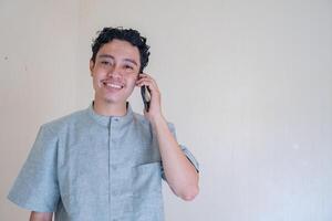 moslem asiatisk man kallelse med smartphone med Lycklig ansikte när ramadan firande. de Foto är lämplig till använda sig av för Ramadhan affisch och muslim innehåll media.