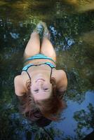 upside ner porträtt av bikini flicka liggande i grund vatten foto
