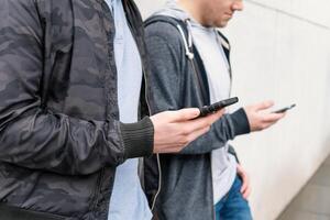 två mobil telefon Beroende manlig tonåringar använder sig av smartphone foto